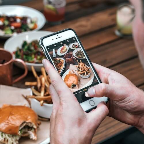 man-taking-photo-of-food-at-restaurant